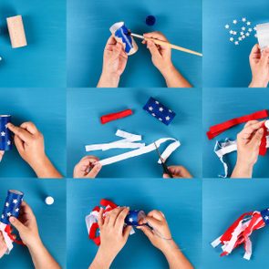 Hands craft a patriotic paper tube with stars and streamers, using blue paint, glue, and scissors on a blue surface.