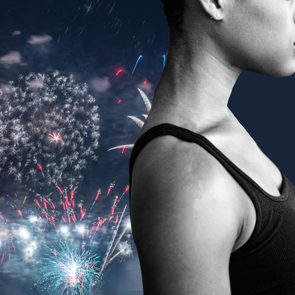 A person stares sideways; their backdrop bursts with vibrant fireworks in a night sky.