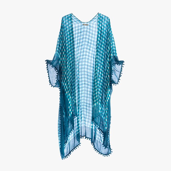 Kaftan hangs against a plain background, featuring a blue checked pattern with tassel trim along the edges.