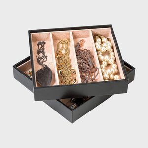 Jewelry box open, displaying assorted necklaces and bracelets in separate compartments, set on a plain gray background.