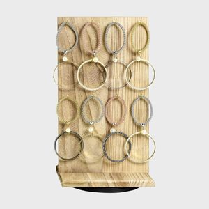 Earrings hang on a wooden display stand, featuring metallic hoops and pearls, arranged neatly on a light wood background.