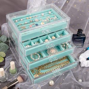 Acrylic jewelry organizer holds assorted pieces in teal-lined compartments against a decorative backdrop, with nail polish and perfume nearby.