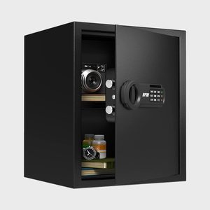 Black safe, partially open, reveals books, camera, watch, and bottles inside; keypad and handle visible on the door.