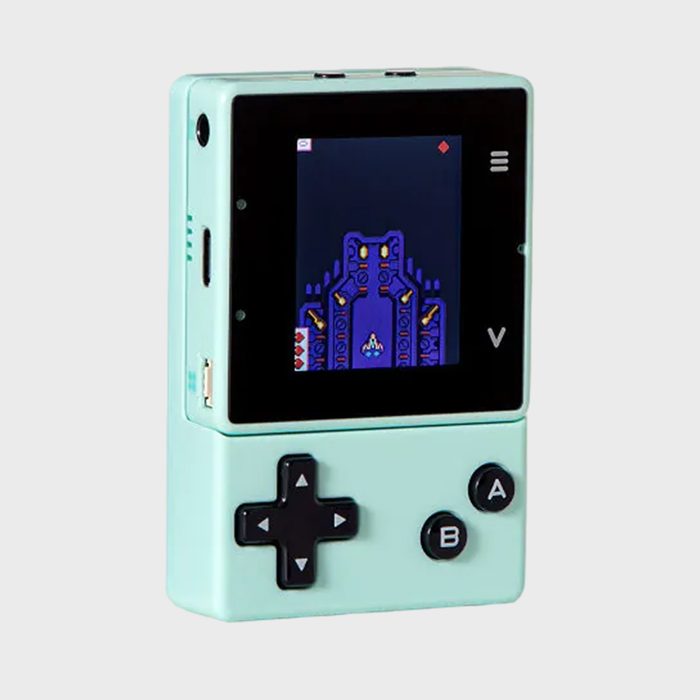Handheld game console displaying a spaceship game, mint green with A, B, and arrow buttons, against a plain, light background.