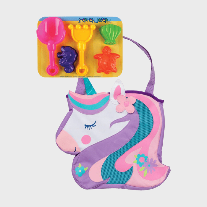 Unicorn-shaped bag with decorative flowers holds colorful sand toys; a yellow rake, pink scoop, and animal molds on a yellow background. Text: â€œStephen Joseph.â€