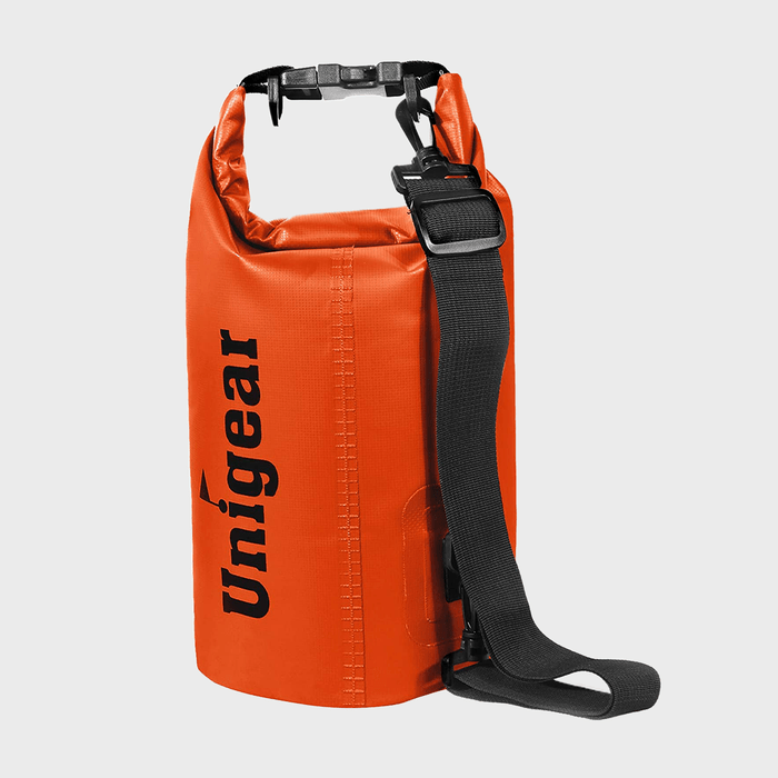 An orange waterproof dry bag stands upright, featuring a black strap and clasp, with 