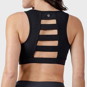 Black sports bra features back cutouts, worn by a person with dark hair, in a neutral studio setting.