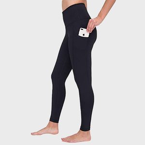 Leggings hold a smartphone in a side pocket; person stands barefoot on a plain background.