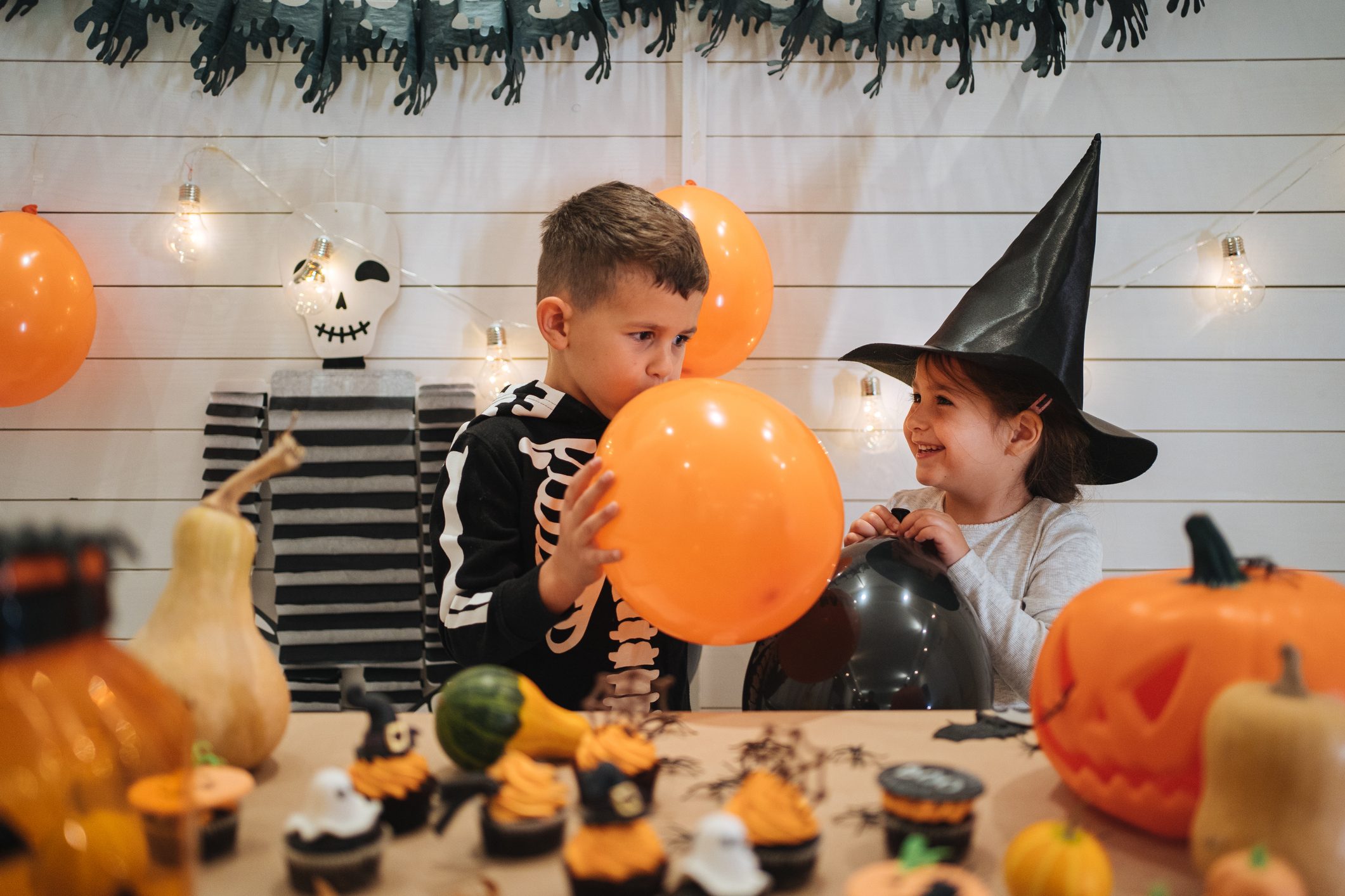 young boy blowing up orange balloon at halloween party for relay race