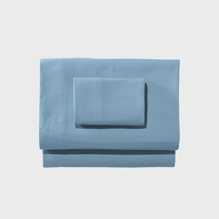 A folded blue bedsheet set rests neatly against a plain white background.