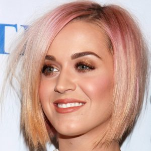 Smiling person with a short, pink-tinted hairstyle against a white backdrop.