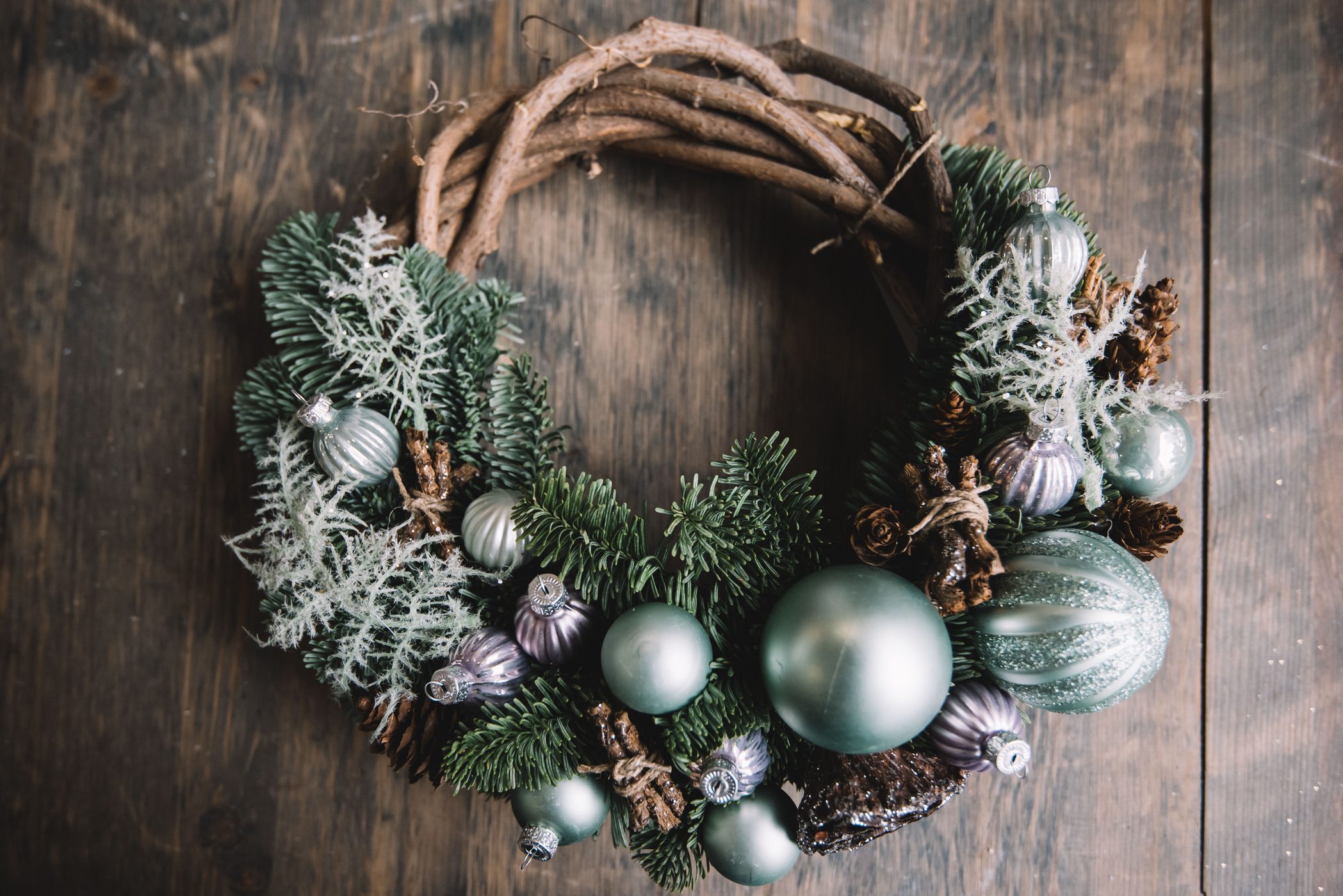 Beautiful festive winter hand made wreath on the rustic wooden table background, top view