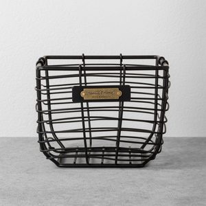 Wire basket sits on a gray surface, holding a sign reading 