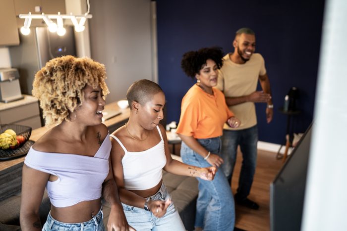 Friends dancing together in front of television at home