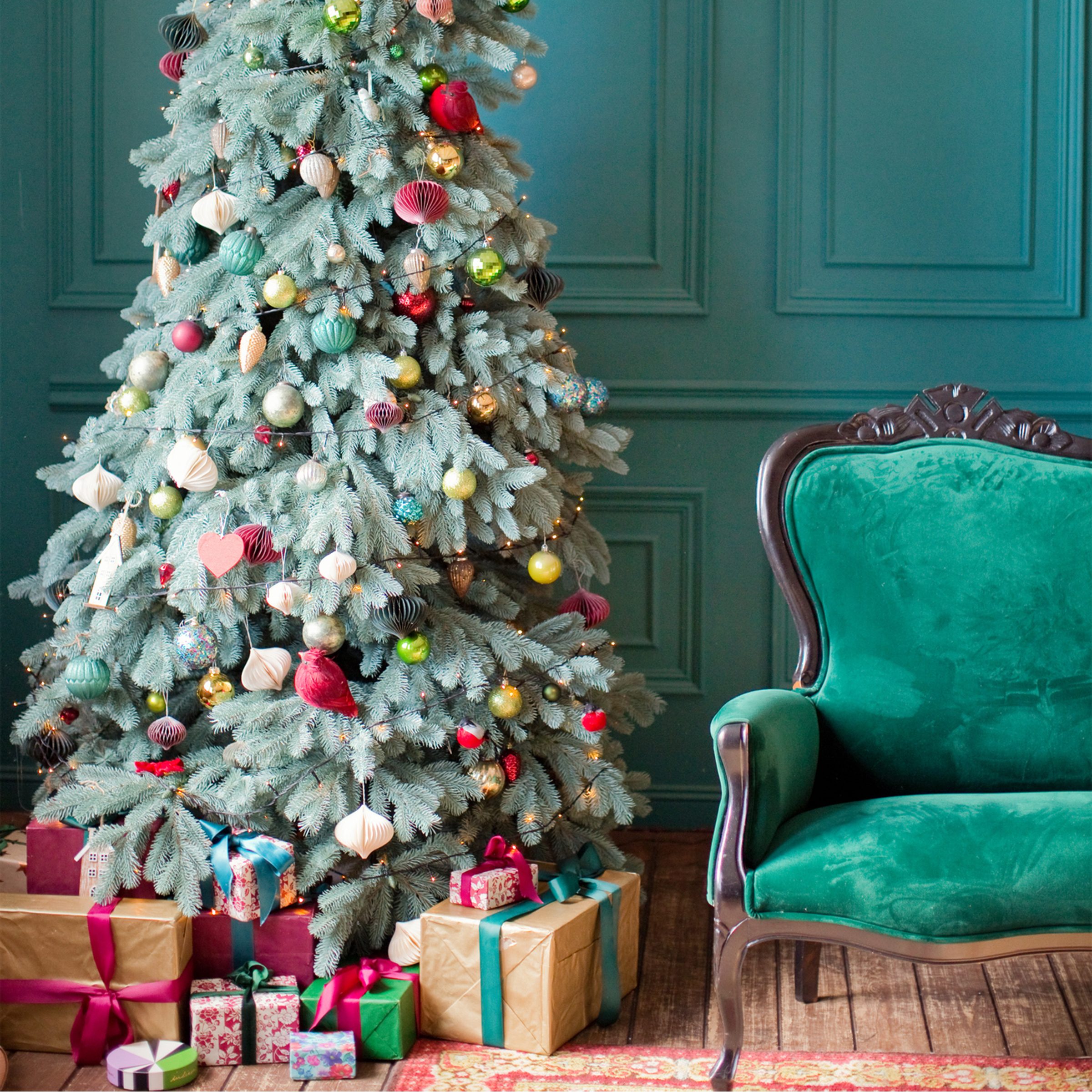 Green Christmas interior. Living room with green walls, green sofa and red, pink and gold Christmas decorations on Christmas tree