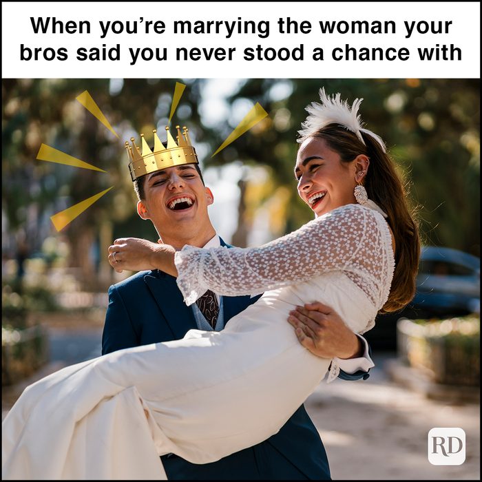 Bride laughing while carrying groom in park on sunny day