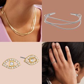 Gold necklaces adorn a woman's neck, silver bangles rest on a surface, eye-shaped earrings displayed, woman wearing a ring holds her hair.