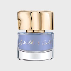 A glass nail polish bottle with gold cap holds pastel blue polish; 
