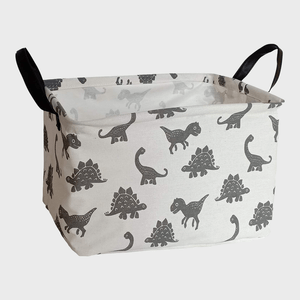 Fabric storage basket displaying dinosaur patterns sits on a light background with black handles on each side.