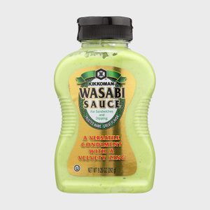 Green bottle displays wasabi sauce label, featuring a tagline about versatility and velvety zing, placed against a plain background.