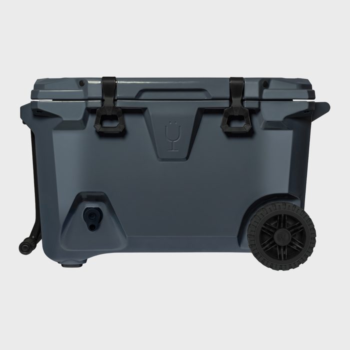 A gray cooler rests on two wheels, with a latch closure and handle, against a plain white background.