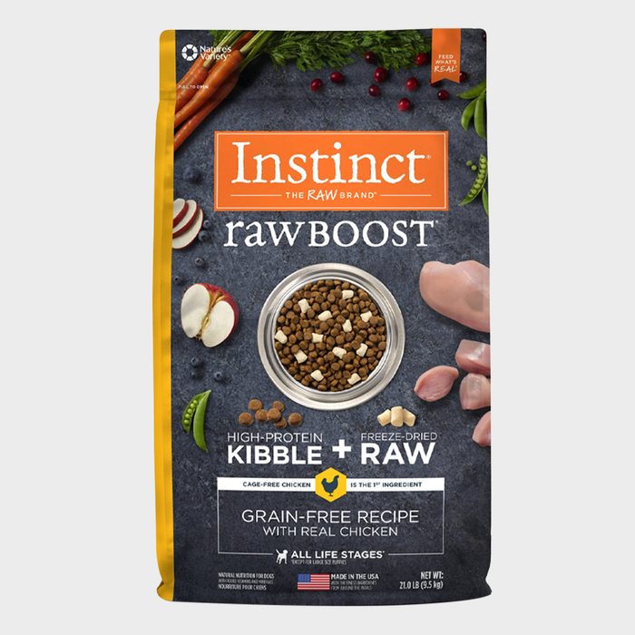 Dog food package displays high-protein kibble with freeze-dried raw in a bowl; surrounded by carrots, apple slices, and chicken pieces.