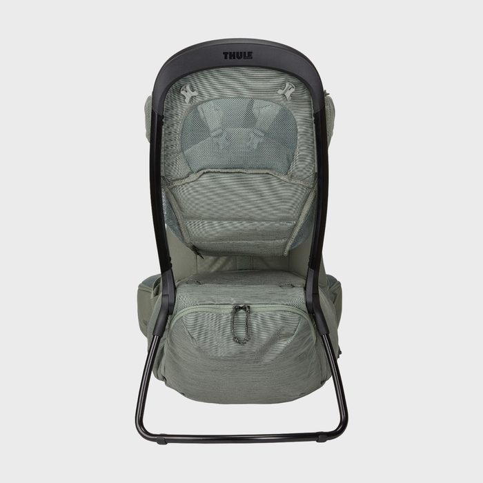 Green child carrier backpack with black frame, standing upright in a plain setting; features include a mesh backrest and lower zippered pocket.