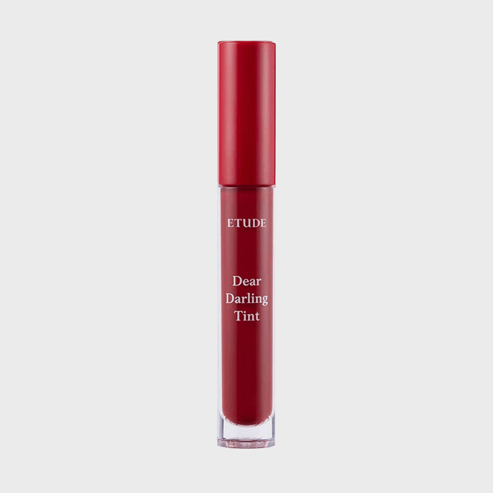 Lip tint bottle stands upright with red cap, labeled 