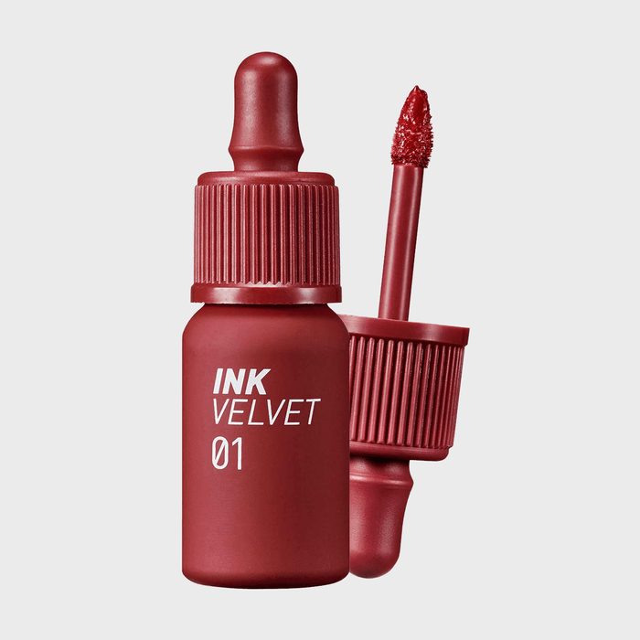Red lip tint bottle with an applicator beside it, labeled 