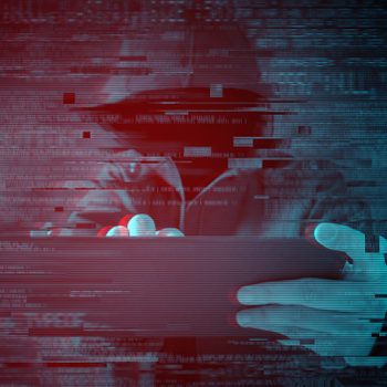 Hooded figure types on tablet, surrounded by glitching digital effects in a dark, red-blue toned environment.