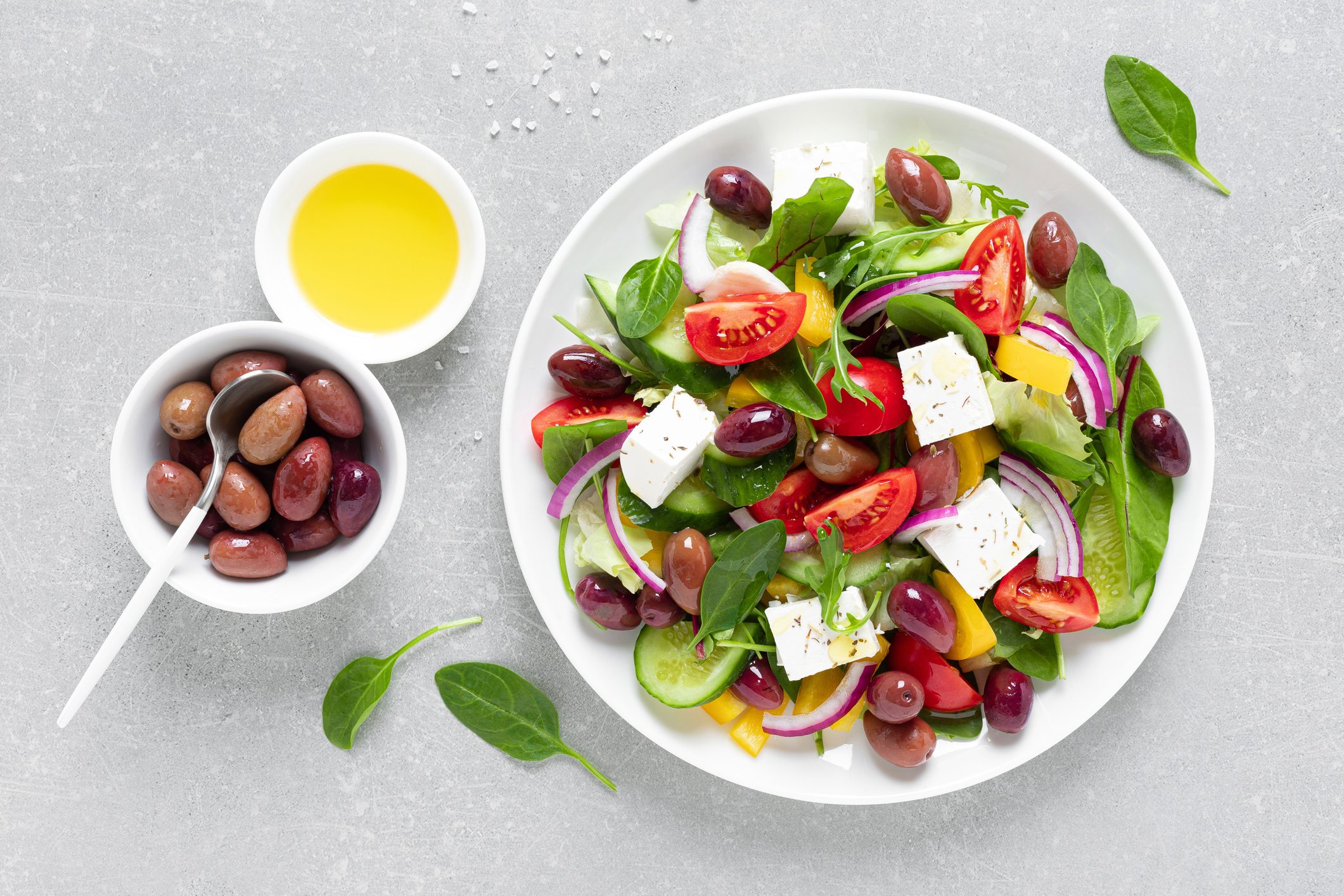 Greek salad with greens, olives and feta chesse on a white plate