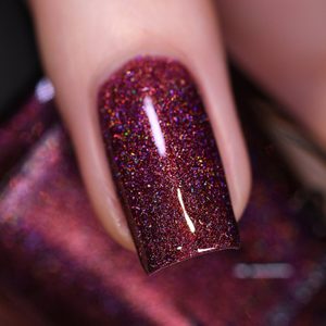 Finger displays glittery burgundy nail polish, shining under light, creating a sparkling effect. Close-up view enhances the shimmer and detail.
