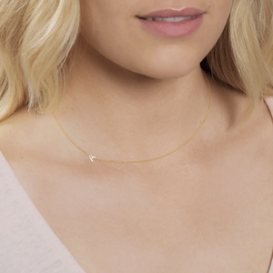 Necklace rests on neck, featuring a tiny triangular pendant, against a skin-toned background with blonde hair partially visible.