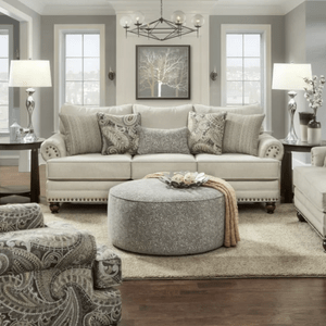 Sofa adorned with patterned cushions, facing a round ottoman, in a sophisticated living room with neutral tones and contemporary decor.
