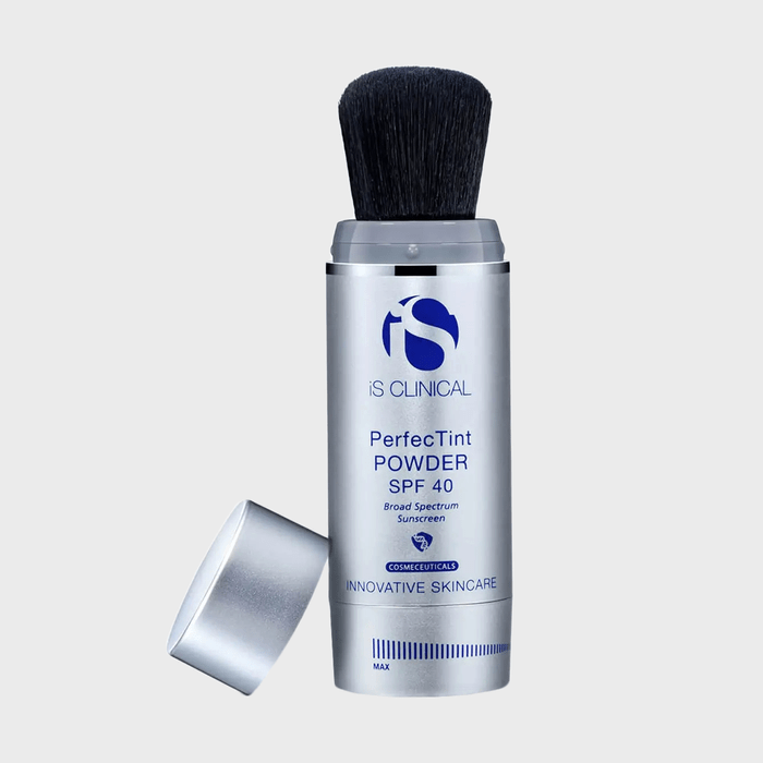The makeup brush dispenses powder with SPF 40 protection, standing upright, lid removed. The context is a clean, neutral background.