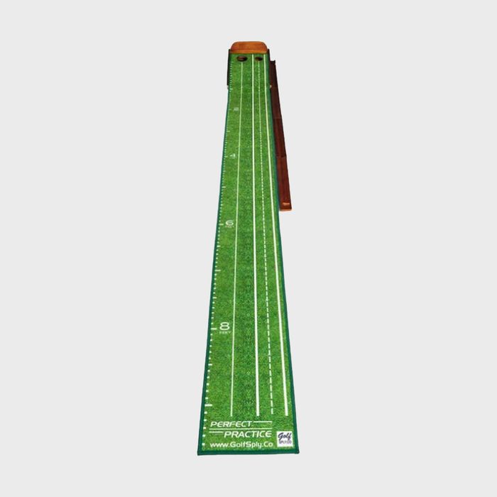 Putting mat lies flat, marked with distance lines and hole, set on the floor for golf practice.