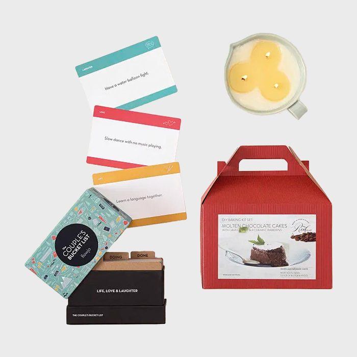 Gift set features activity cards, a candle, and a chocolate cake baking kit, arranged on a light background, suggesting a romantic theme.