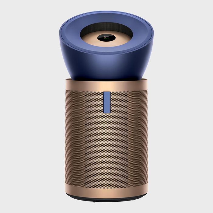 A cylindrical air purifier sits idle, featuring a blue top and bronze perforated body, against a plain gray background.