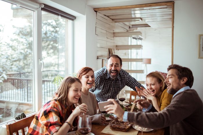 friends laughing at something on someones phone at the dinner table