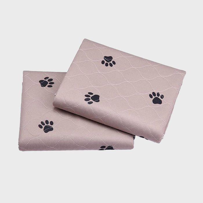 Folded quilted fabric with paw prints lies stacked, displaying wave-like stitching pattern against a plain background.