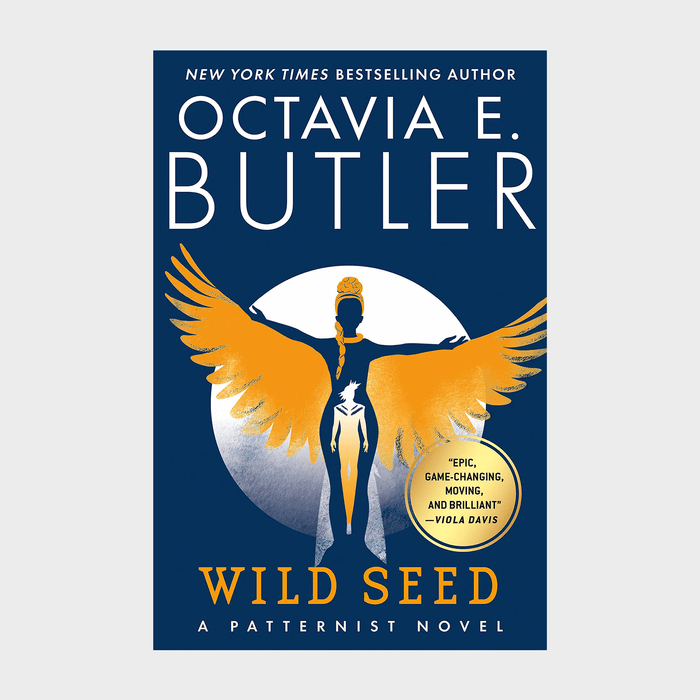 Figure stands with golden wings outspread, set against blue background. Text: 