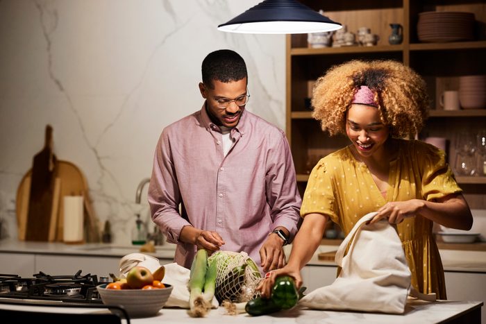 Young Couple Unpacking Vegetables In Kitchen