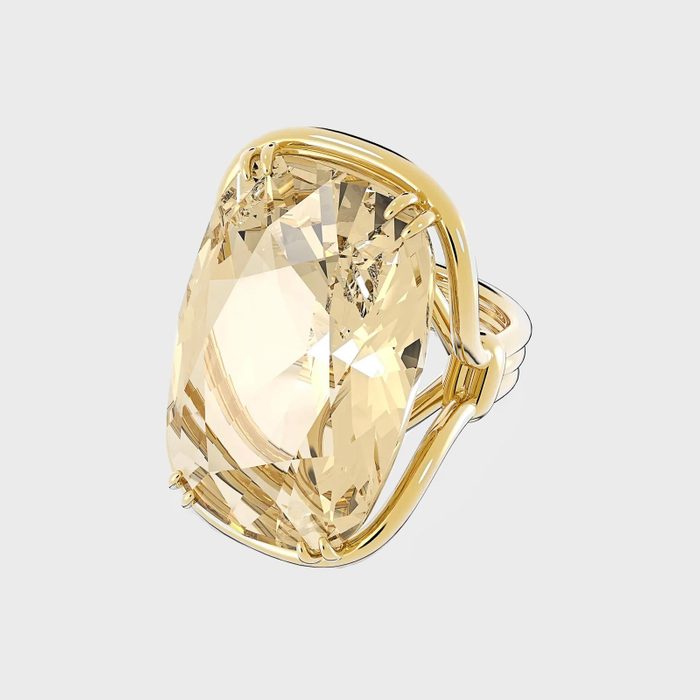 A large, faceted, pale yellow gemstone set in a gold ring, displayed against a plain white background.