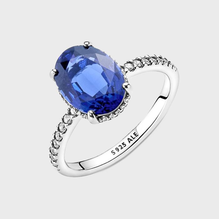 Ring displays blue oval gemstone, surrounded by smaller stones on band; inscribed text reads 