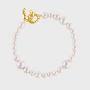 Pearl necklace featuring a gold, abstract clasp, set against a plain white background.