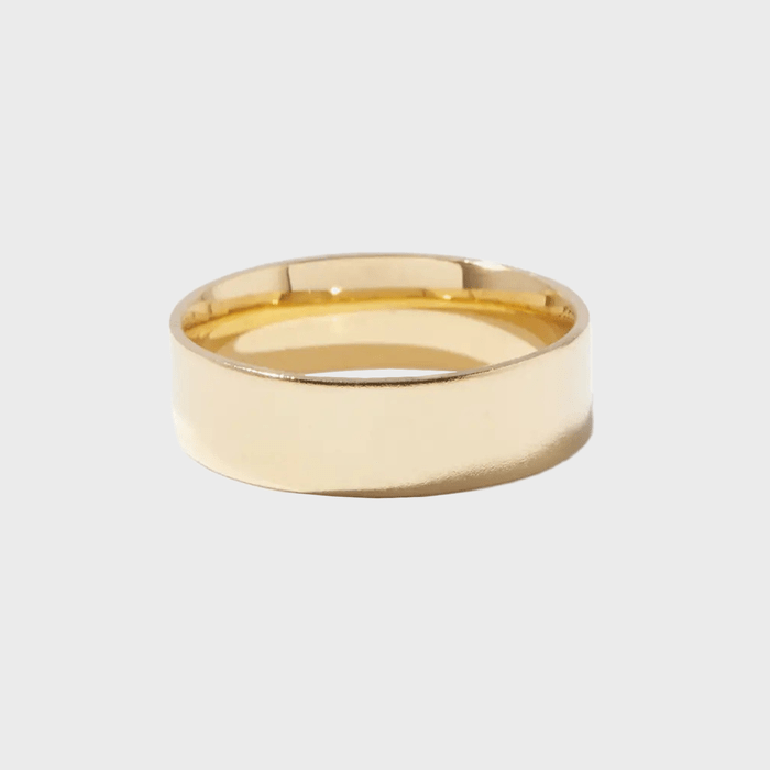 Golden band resting against a neutral background, reflecting light on its smooth surface.