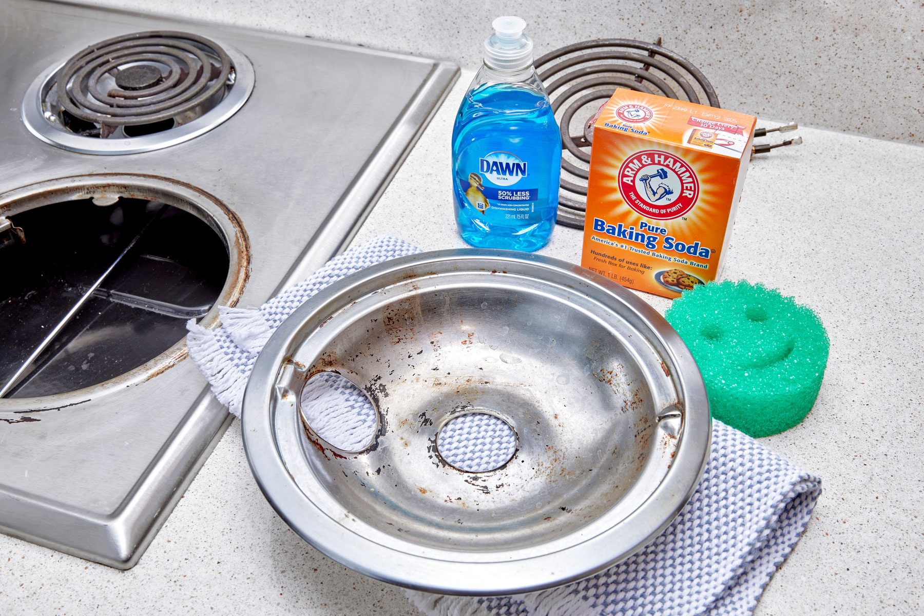 electric stove drip pan removed from stove and arranged near cleaning supplies