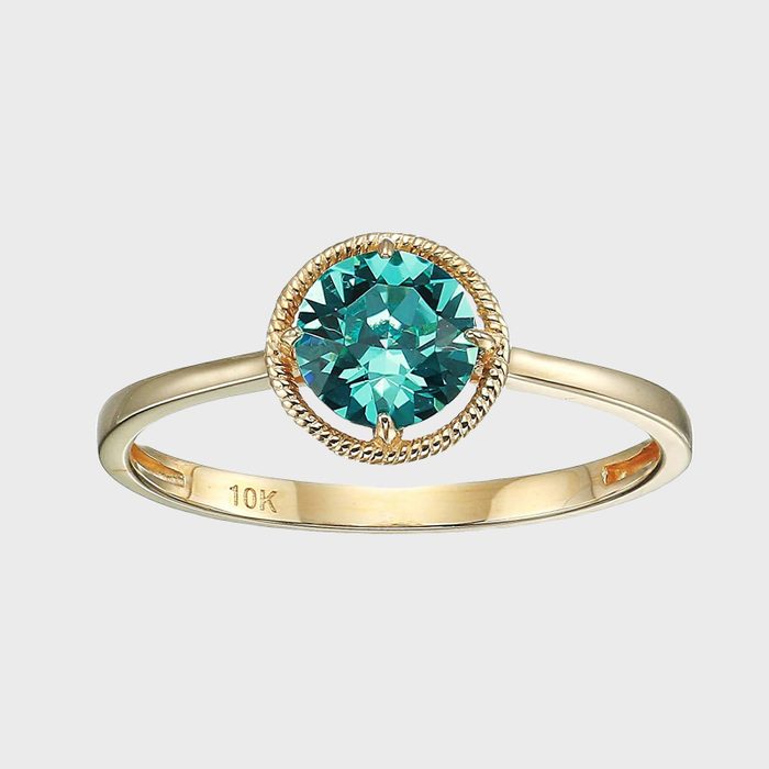 Gold ring showcases blue gemstone, surrounded by rope design, with 