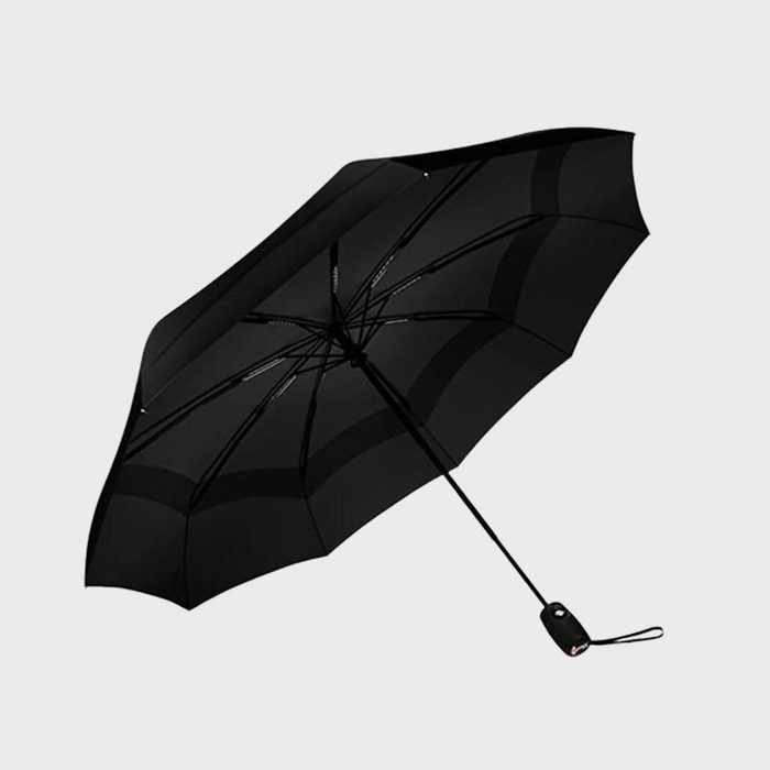 Black umbrella open, angled view, with a handle and wrist strap; set against a plain gray background.