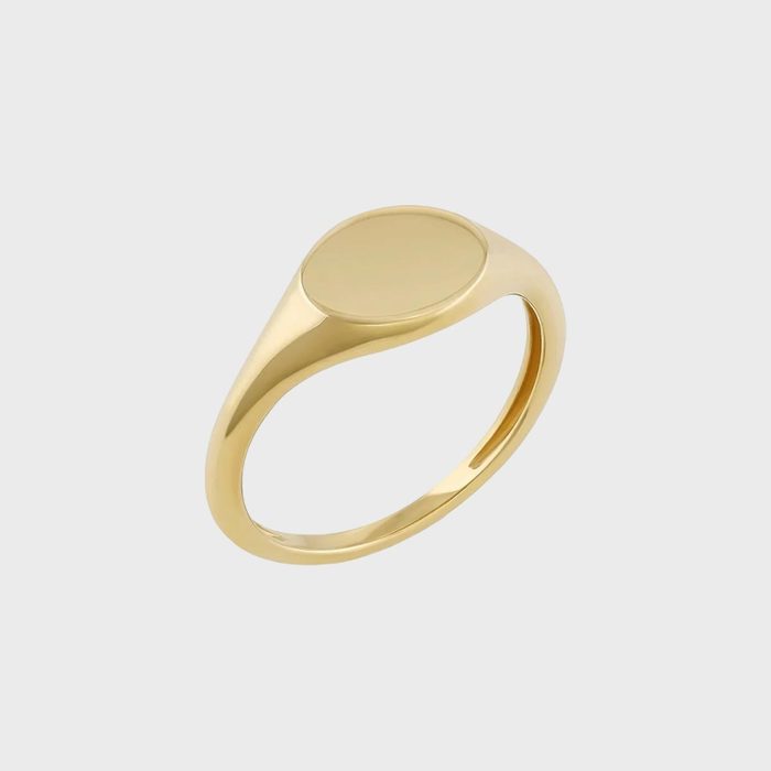 A gold ring with a flat, circular top, displayed on a plain gray background.